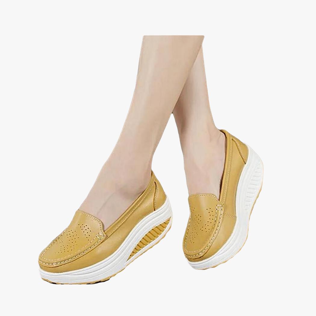 on voit une femme mais seulement ses pieds avec des mocassins respirants colorés à plateforme de couleur camel