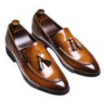 Mocassins habillés à glands en cuir véritable pour homme sur fond gris très clair.