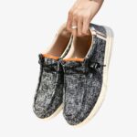 Paire de mocassins pour homme en toile de couleur grise avec des petites taches noires et une semelle blanche.