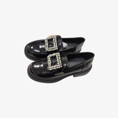 Mocassins pour femme en cuir verni noir, élégants et brillants. Ces chaussures sont ornées d'une grande boucle décorative sertie de strass scintillants sur le dessus, apportant une touche glamour et sophistiquée, parfaites pour une tenue chic.