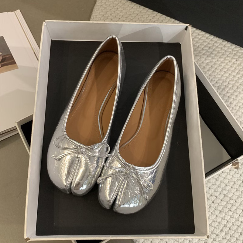 Ballerines plates tabi avec noeud décoratif de couleur argentée dans une boite ouverte