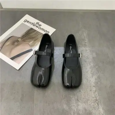 Paire de ballerines Mary Jane cuir fendu noir pour femmes - Style Tabi sur un sol gris devant un magazine